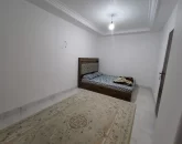 تخت خواب با روتختی سفید مشکی و فرش کرمی رنگ اتاق خواب آپارتمان در خلیل شهر