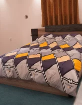 تخت خواب با روتختی رنگی و پرده آجری رنگ اتاق خواب ویلا در عباس آباد