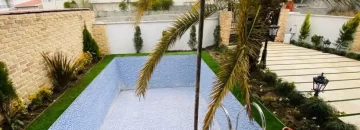 محوطه سنگ فرش شده و باغچه سرسبز اطراف استخر ویلا باغ در بهشهر